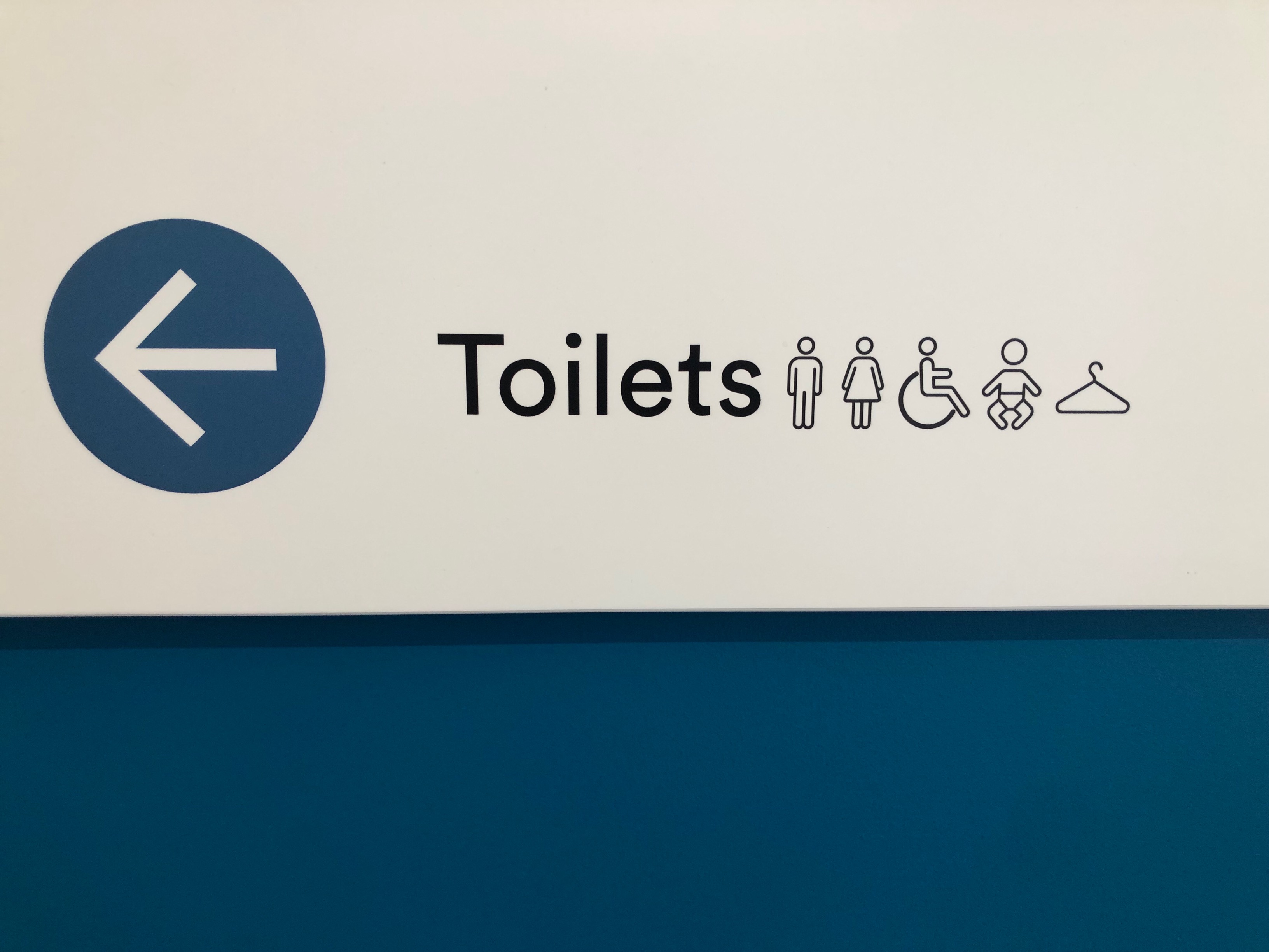 Image of signage saying Toilets, with icons of male, female, wheelchair, infant and coathanger with an arrow pointing to the left