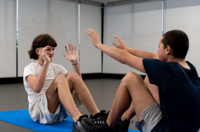 2 teenagers high fiving each other in a sit up position